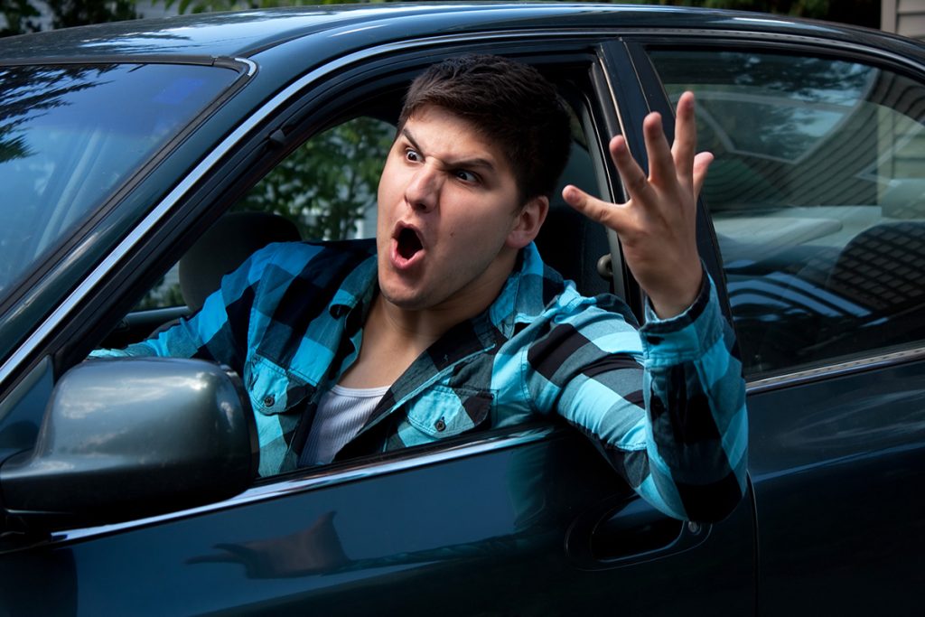 Man Expressing Road Rage An irritated young man driving a vehicle is expressing his road rage.